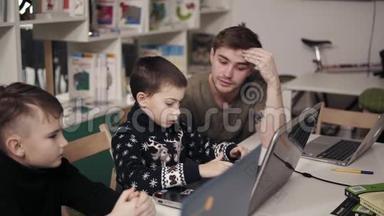 20`的年轻男教师向两个小男孩讲解一些东西，教他们如何使用笔记本电脑